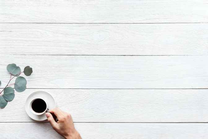 person holding white ceramic teacup with black coffee